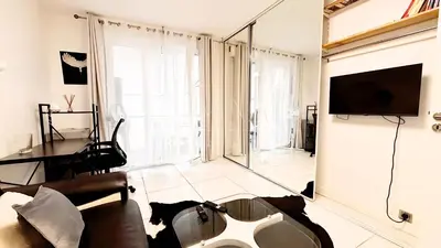 a living room with a tv and a couch and a table at Proche Centre ville, 1 chambre, balcon - Palmazur Vacances in Le Cannet