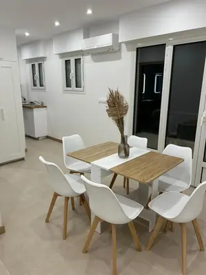 a dining room with a wooden table and white chairs at Joyaux cannois in Cannes