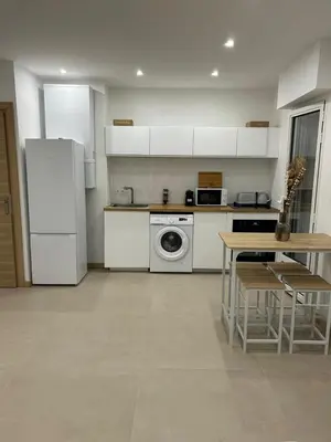 a kitchen with white appliances and a table with chairs at Joyaux cannois in Cannes