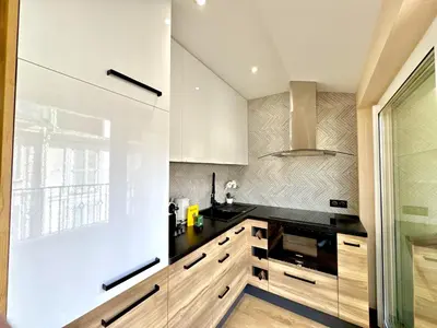 a kitchen with white cabinets and black counter tops at Top floor apartment in Cannes