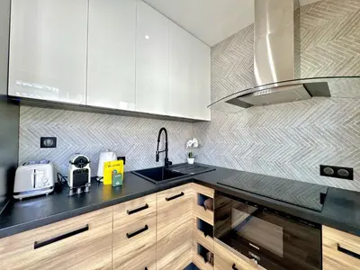 a kitchen with white cabinets and a black counter top at Top floor apartment in Cannes