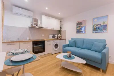 a living room with a blue couch and a table at Azur Loft Beauséjour Heart of Cannes in Cannes