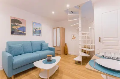 a living room with a blue couch and a table at Azur Loft Beauséjour Heart of Cannes in Cannes