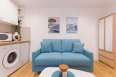 a living room with a blue couch and a washing machine at Azur Loft Beauséjour Heart of Cannes in Cannes