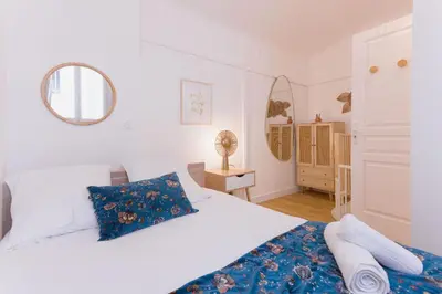 a white bedroom with a bed and a mirror at Azur Loft Beauséjour Heart of Cannes in Cannes