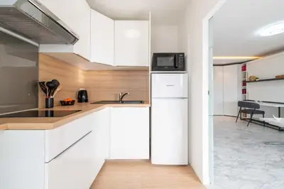 a kitchen with white cabinets and a refrigerator at Studio in a Prestigious Residence Close to the City Centre in Cannes