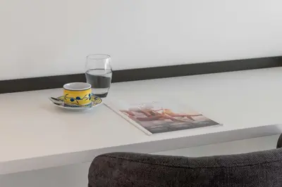 a table with a cup and a glass of water and a magazine at Studio in a Prestigious Residence Close to the City Centre in Cannes