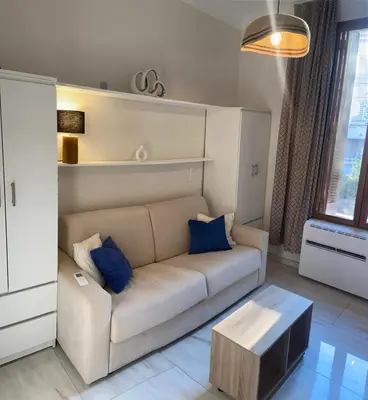 a living room with a white couch and blue pillows at Studio climatisé 5 min centre Cannes in Cannes