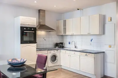 a kitchen with white cabinets and a washer and dryer at Cozystay 1802 One bedroom in the Heart of Cannes in Cannes