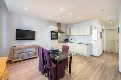 a kitchen with a glass table and purple chairs at Cozystay 1802 One bedroom in the Heart of Cannes in Cannes