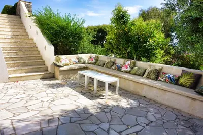 a bench with pillows and a table on a patio at Ref JOA - Palmes d Or Properties in Cannes