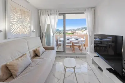 a white living room with a couch and a television at Le RivieraPeacefulSwimming poolCar parkSeafront in Cannes