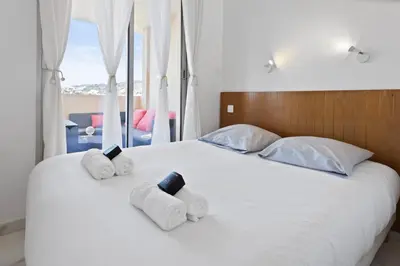 a bedroom with a white bed with towels on it at Le RivieraPeacefulSwimming poolCar parkSeafront in Cannes