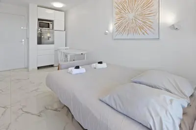 a white bedroom with a large bed with two pillows at Le RivieraPeacefulSwimming poolCar parkSeafront in Cannes