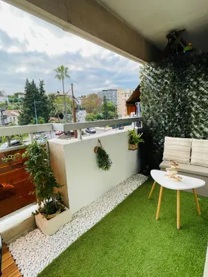 a small balcony with a white table and green grass at Charmant studio en centre ville in Le Cannet