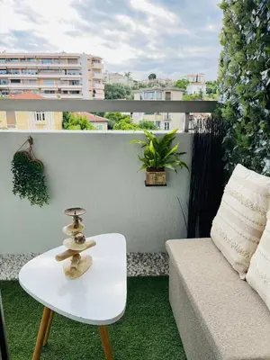 a white coffee table and a couch on a balcony at Charmant studio en centre ville in Le Cannet