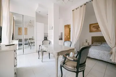a bedroom with a table and chairs and a bed at Le Petit Palais, 100m des plages in Cannes