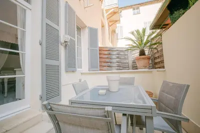a glass table and chairs on a balcony with windows at Le Petit Palais, 100m des plages in Cannes