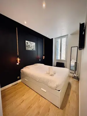 a bedroom with a large white bed with a black wall at Très Bel appartement proche plage et palais du festival in Cannes