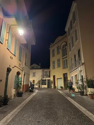 a man walking down a street at night at Très Bel appartement proche plage et palais du festival in Cannes