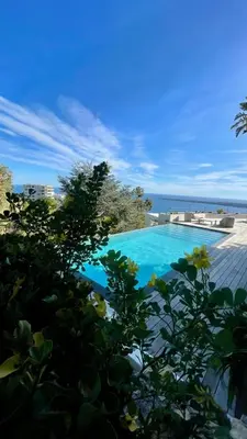 a deck with two chairs and a table and a pool at Villa Baie Des Iles in Cannes
