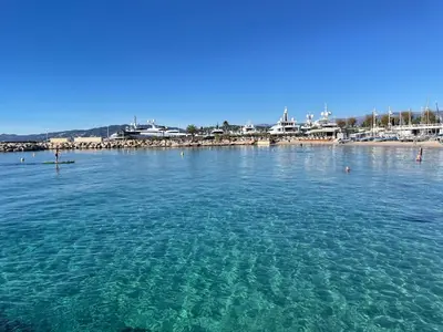 a beach with a group of people standing on a pier at Le jardin du Palm Beach - domaine de standing in Cannes