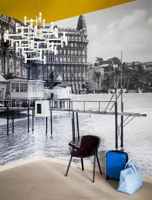 a chair and suitcase sitting in front of a building at OKKO Hotels Cannes Centre in Cannes