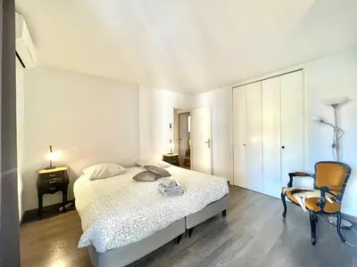 a white bedroom with a bed and a chair at Cannes Center by Welcome to Cannes in Cannes
