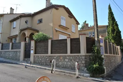 a house with a stone wall and a fence at Le Calme au Centre Ville à 10 minutes à pied de la Croisette et des plages in Cannes