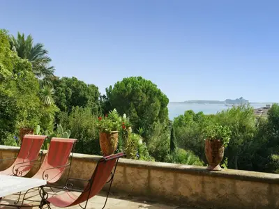 three chairs and a table on a wall with a view of the ocean at Scenic villa in Cannes with private pool in Cannes