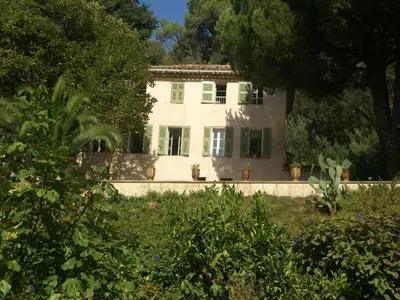 a large white house with green shutters and trees at Scenic villa in Cannes with private pool in Cannes