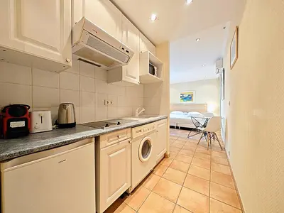 a kitchen with white cabinets and a washer and dryer at Viva Riviera Residence Commandant André in Cannes
