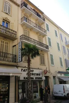 a building with a palm tree in front of it at Large 1 Bedroom with Balcony City Centre in Cannes