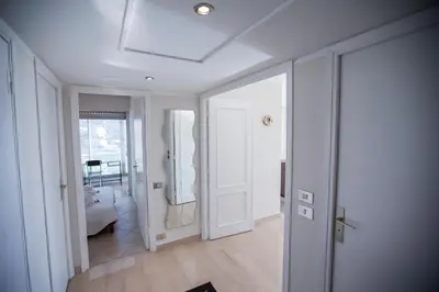 a hallway with white walls and a door with a mirror at Central Park by Connexion in Cannes
