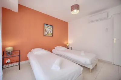 two beds in a room with an orange wall at IMMOGROOM - Renovated apartment - Terrace - AC in Cannes