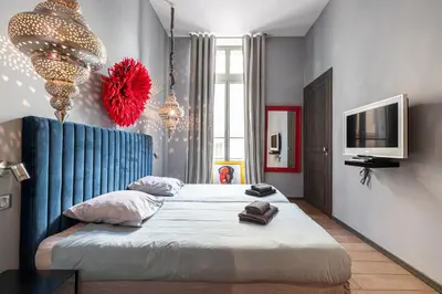 a bedroom with two beds and a television and chandeliers at The Cosmopolitan Lodge in Cannes
