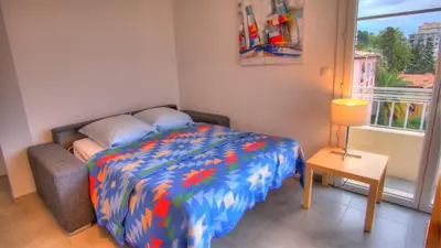 a bedroom with a bed with a colorful comforter and a window at Beau 2 pièces 3 étoiles Vue Mer Garage Privé 150m plages wifi in Cannes