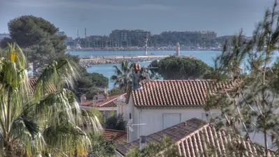 a white house with a beach in the background at Beau 2 pièces 3 étoiles Vue Mer Garage Privé 150m plages wifi in Cannes