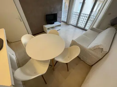a living room with a table and chairs and a couch at Appartements Villa Rimbaud by Connexion in Cannes