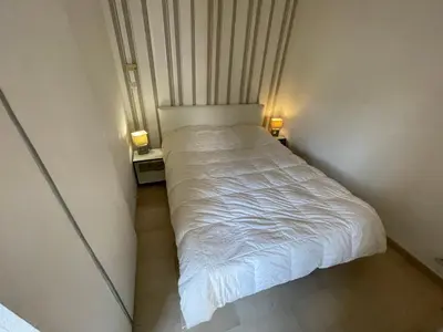 a small bed in a small room with two lamps at Appartements Villa Rimbaud by Connexion in Cannes