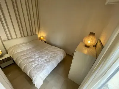 a small bedroom with a white bed and a lamp at Appartements Villa Rimbaud by Connexion in Cannes
