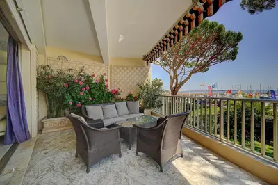 a patio with a couch and chairs on a balcony at IMMOGROOM- Huge Terrace - Panoramic Sea View - 1min from Beach in Cannes