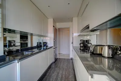 a large kitchen with white cabinets and stainless steel appliances at IMMOGROOM- Huge Terrace - Panoramic Sea View - 1min from Beach in Cannes