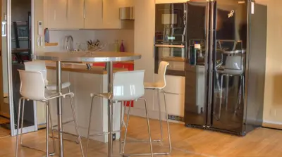 a kitchen with a bar with white chairs and a refrigerator at 3 pièces 4 étoiles Vue Mer Parking Fibre 500m Palais Festivals in Cannes