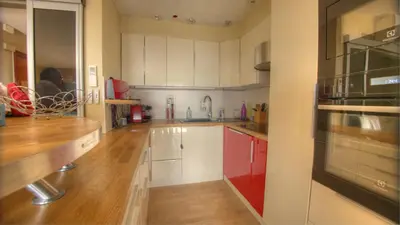 a kitchen with white cabinets and a wooden floor at 3 pièces 4 étoiles Vue Mer Parking Fibre 500m Palais Festivals in Cannes