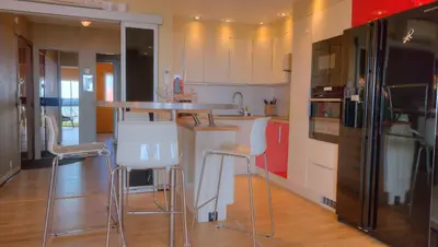 a kitchen with white cabinets and bar stools at 3 pièces 4 étoiles Vue Mer Parking Fibre 500m Palais Festivals in Cannes