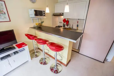 a kitchen with red bar stools and a counter at Appartement et Parking Cannes Center by Connexion in Cannes
