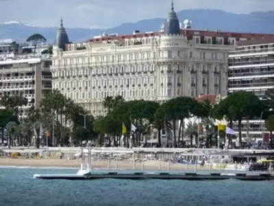 a large white building with a boat in the water at APPART' CANNES in Cannes