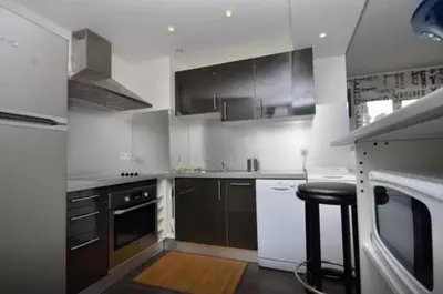 a kitchen with black and white appliances and a stool at APPART' CANNES in Cannes