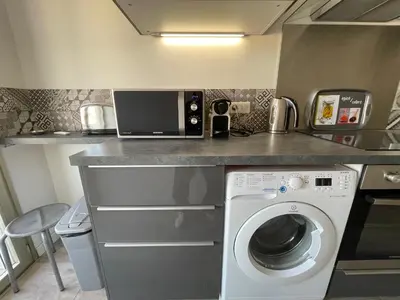 a kitchen with a washing machine and a microwave at Le Suquetan in Cannes